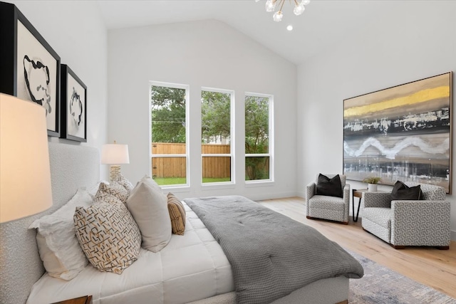 bedroom featuring light wood-type flooring, a chandelier, and vaulted ceiling