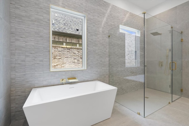 bathroom with tile walls, tile patterned floors, plus walk in shower, and a wealth of natural light