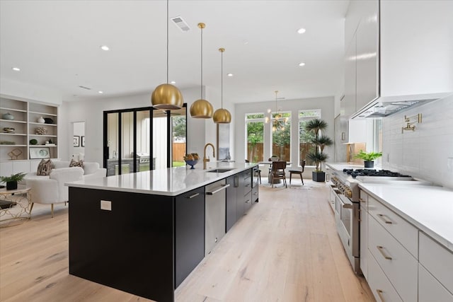 kitchen featuring an island with sink, hanging light fixtures, appliances with stainless steel finishes, and white cabinets