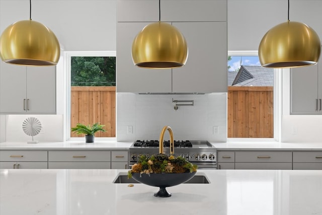 kitchen with gray cabinets, decorative light fixtures, high end stainless steel range oven, and tasteful backsplash