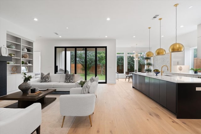 living room featuring light hardwood / wood-style floors, an inviting chandelier, and sink