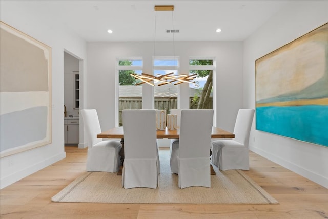 dining area with light hardwood / wood-style floors and a chandelier