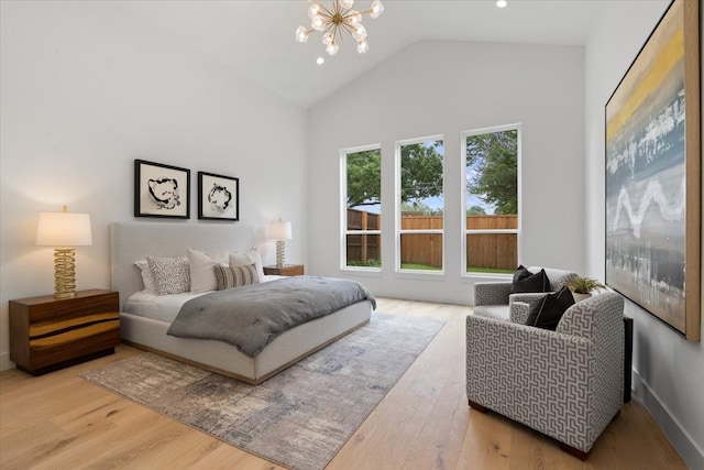 bedroom with hardwood / wood-style flooring, high vaulted ceiling, and a chandelier