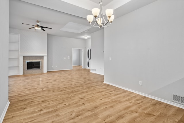 unfurnished living room with light hardwood / wood-style flooring, a tile fireplace, and ceiling fan with notable chandelier