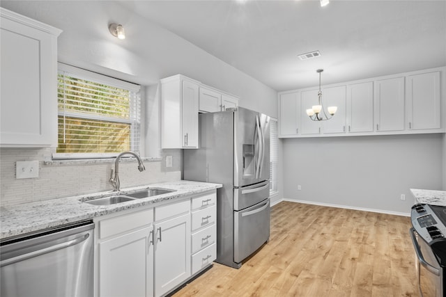 kitchen featuring white cabinets, hanging light fixtures, light hardwood / wood-style flooring, sink, and stainless steel appliances