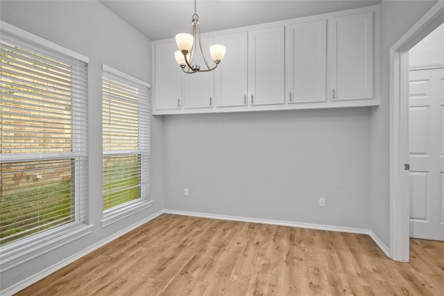 unfurnished dining area featuring an inviting chandelier and light hardwood / wood-style flooring