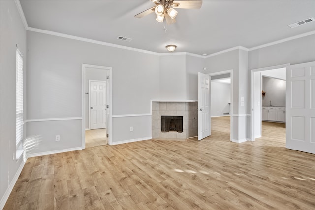 unfurnished living room with light hardwood / wood-style flooring, a tiled fireplace, ceiling fan, and crown molding