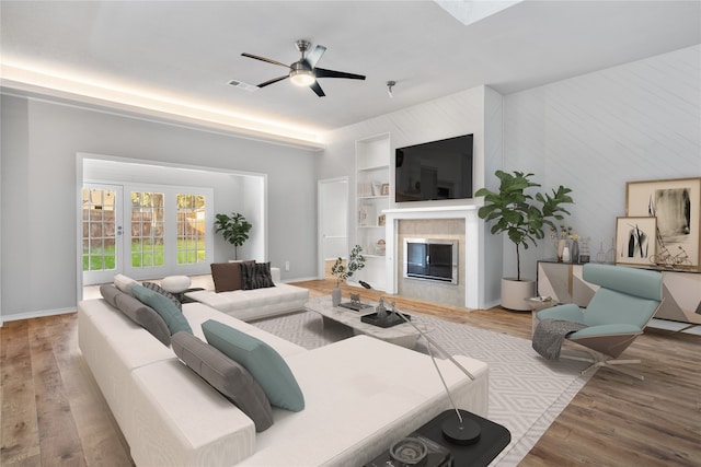 living room featuring a fireplace, light wood-type flooring, and ceiling fan