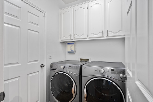 clothes washing area with cabinets and washing machine and clothes dryer