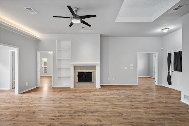 unfurnished living room featuring a tiled fireplace, a textured ceiling, light hardwood / wood-style flooring, and ceiling fan