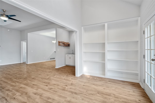 unfurnished living room featuring ceiling fan, sink, and light wood-type flooring