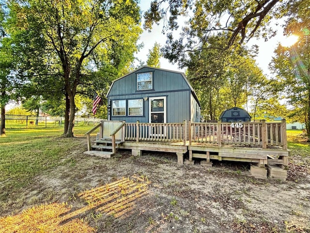 back of property with a wooden deck and a lawn