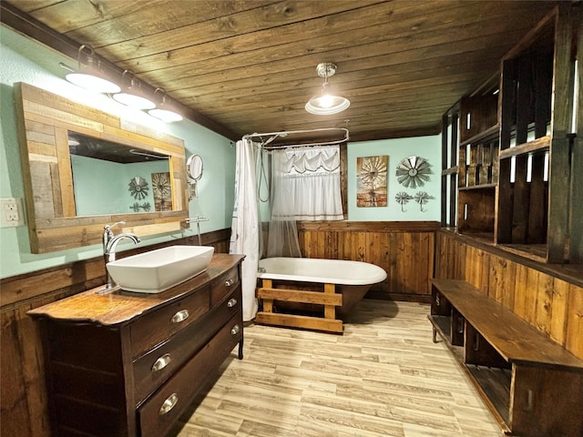 bathroom with wood walls, wood-type flooring, wooden ceiling, a tub, and vanity