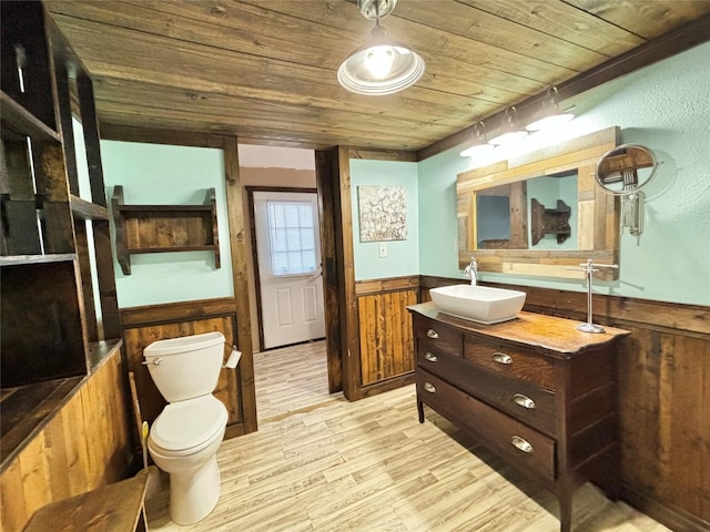 bathroom with wood walls, toilet, wood ceiling, hardwood / wood-style flooring, and vanity