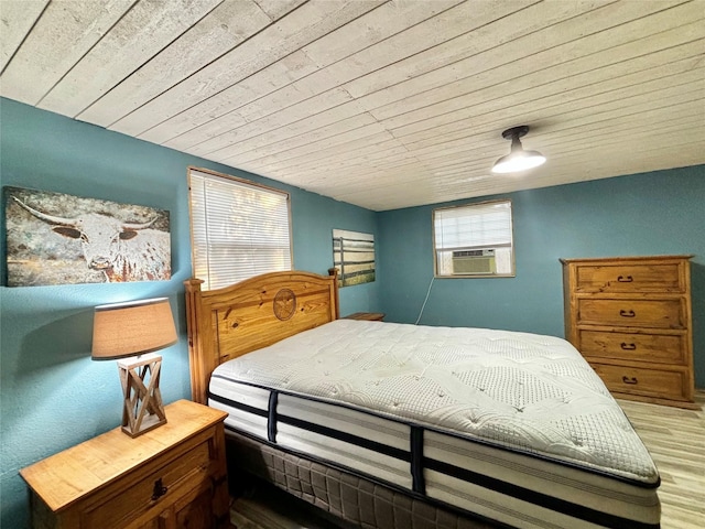 bedroom featuring cooling unit, wood ceiling, hardwood / wood-style flooring, and multiple windows