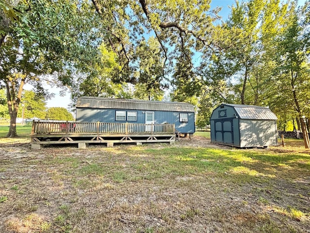 rear view of house with a storage shed, a yard, and a deck