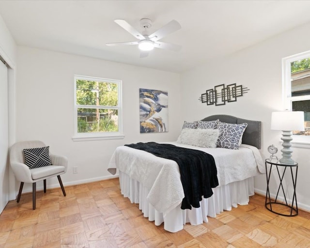 bedroom featuring multiple windows, ceiling fan, and light parquet floors