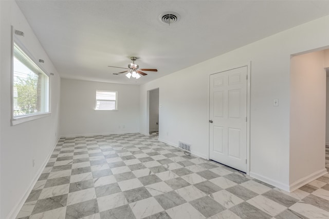 empty room with ceiling fan and a healthy amount of sunlight