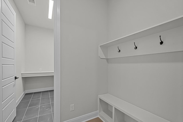 mudroom with dark tile patterned floors, visible vents, and baseboards