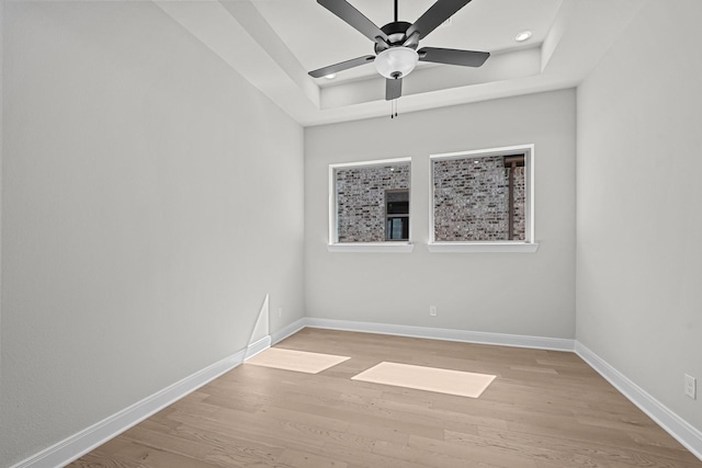 spare room with ceiling fan, baseboards, a tray ceiling, recessed lighting, and light wood-style floors