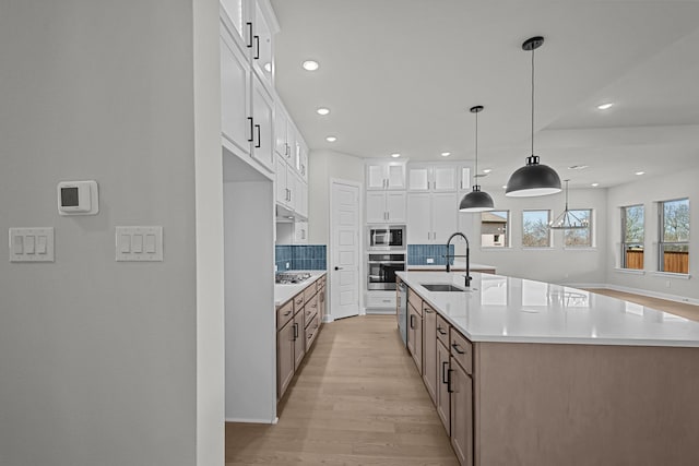 kitchen featuring a sink, tasteful backsplash, stainless steel appliances, white cabinets, and light wood finished floors