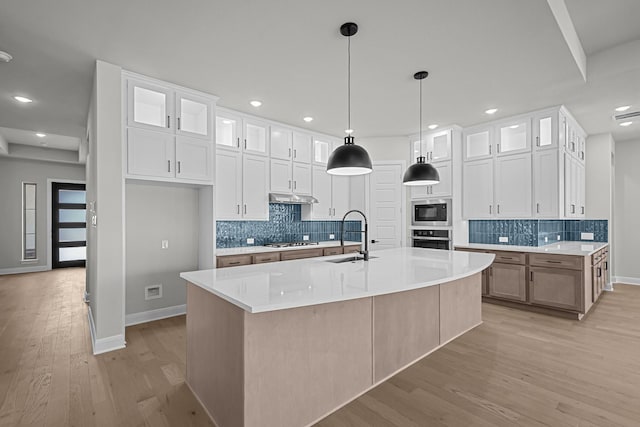 kitchen with white cabinets, stainless steel appliances, under cabinet range hood, and a sink