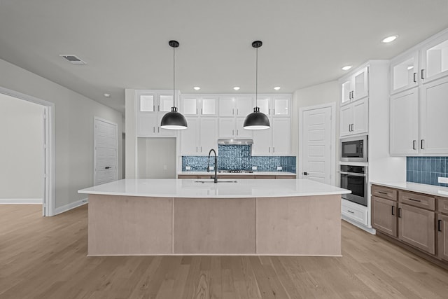 kitchen with visible vents, a sink, light countertops, stainless steel oven, and built in microwave