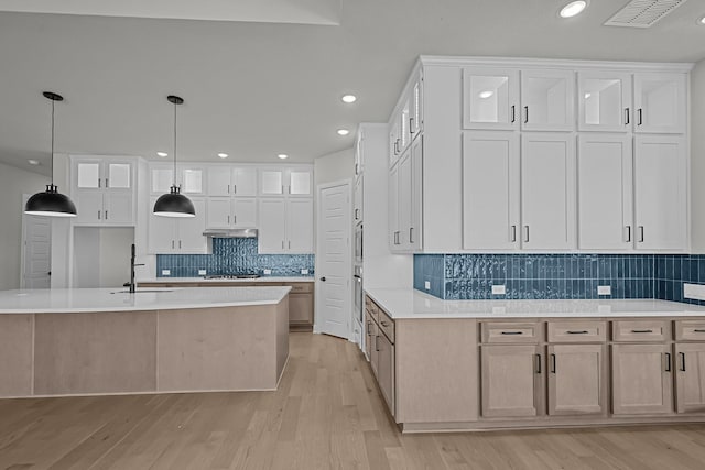 kitchen with light wood-style flooring, visible vents, stovetop, and light countertops