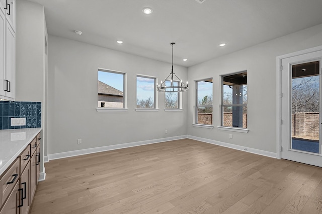 unfurnished dining area featuring recessed lighting, light wood-type flooring, baseboards, and an inviting chandelier