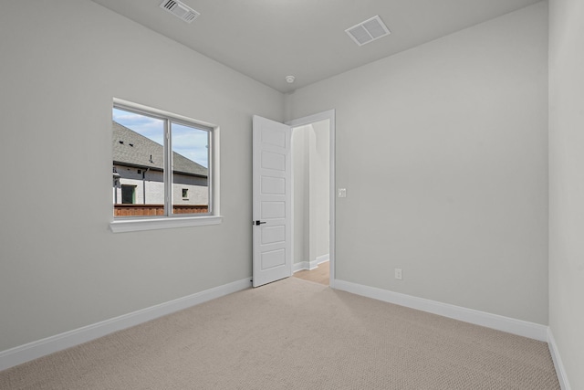 unfurnished room with visible vents, light carpet, and baseboards