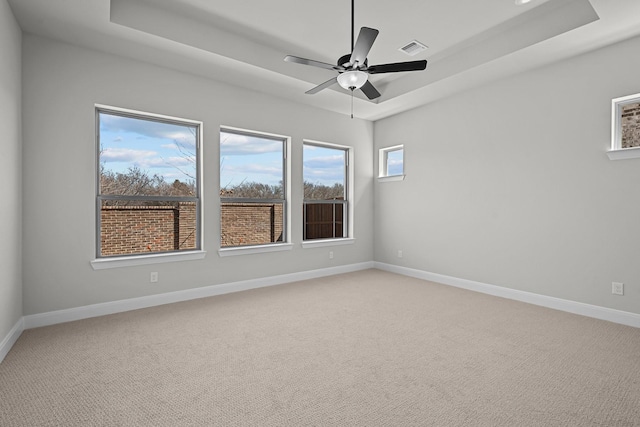 empty room with a raised ceiling, baseboards, and visible vents