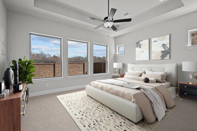 carpeted bedroom featuring visible vents, baseboards, and a tray ceiling