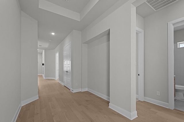 hallway featuring visible vents, baseboards, and light wood-style floors