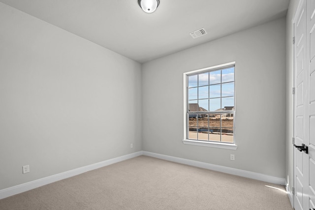 unfurnished room with visible vents, light colored carpet, and baseboards