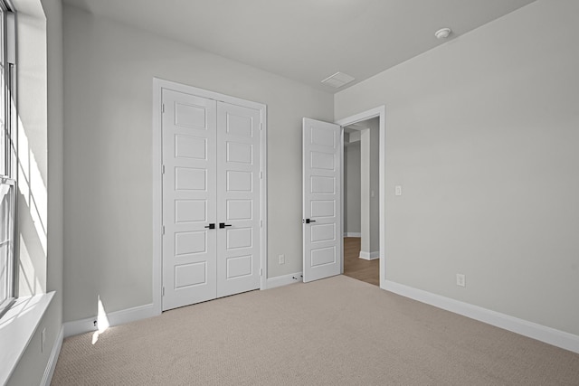 unfurnished bedroom with carpet, a closet, and baseboards