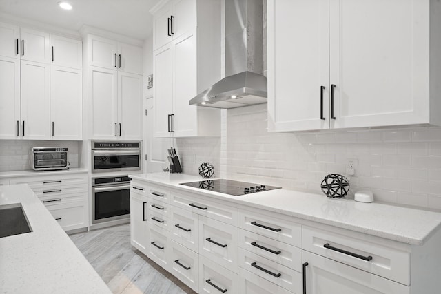 kitchen featuring light stone countertops, wall chimney range hood, light wood-type flooring, and white cabinetry