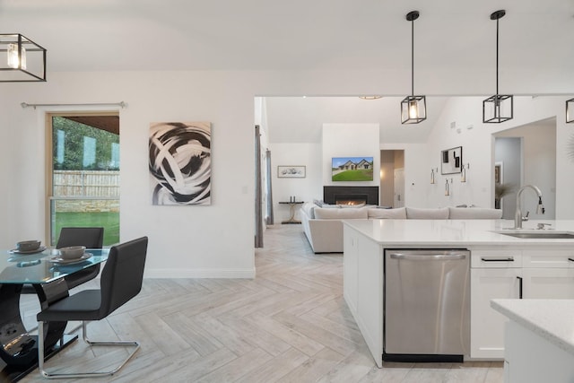 kitchen featuring pendant lighting, sink, light parquet flooring, stainless steel dishwasher, and white cabinetry