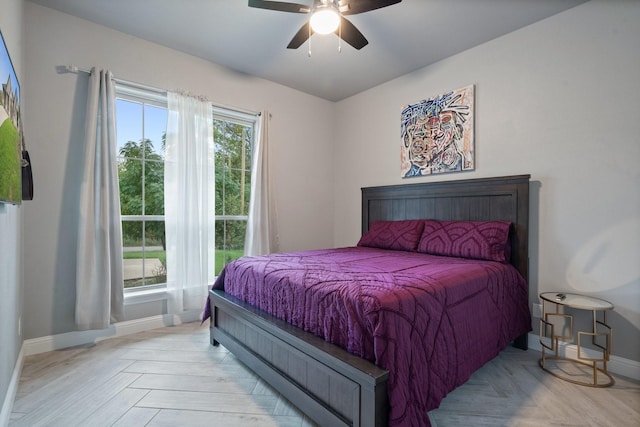 bedroom featuring ceiling fan, multiple windows, and light parquet flooring