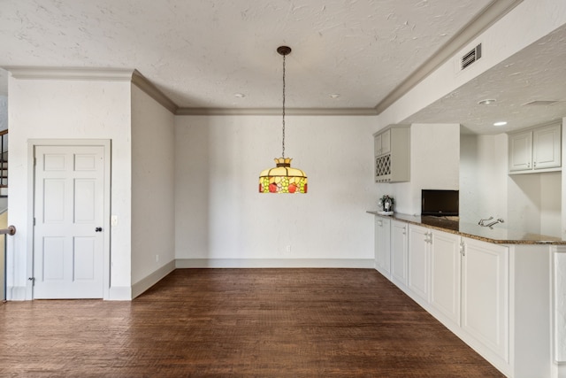 kitchen featuring white cabinets, hanging light fixtures, kitchen peninsula, dark stone countertops, and dark hardwood / wood-style flooring