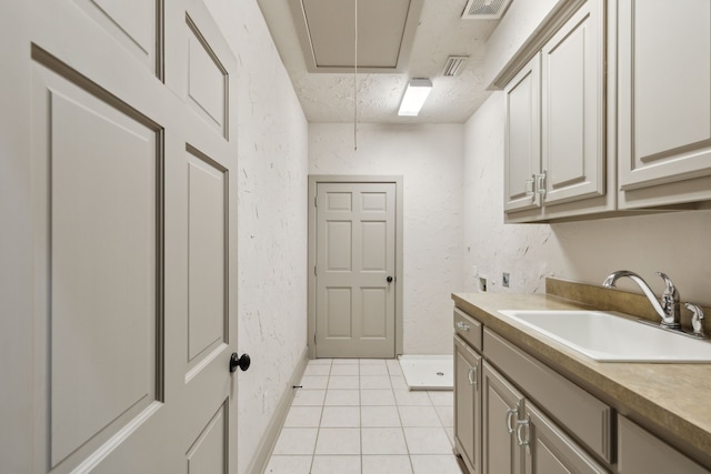 laundry area featuring sink, light tile patterned floors, and cabinets