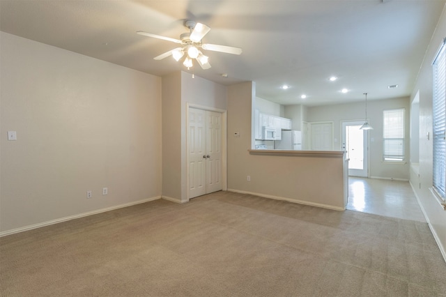 unfurnished living room featuring ceiling fan and light carpet