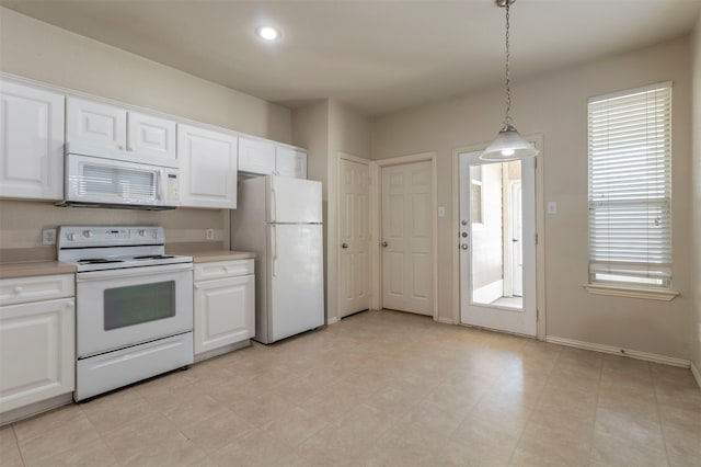 kitchen with white appliances, hanging light fixtures, and white cabinetry