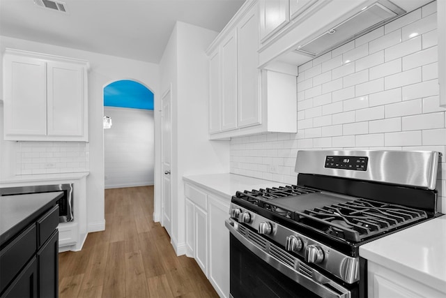 kitchen with tasteful backsplash, stainless steel gas range, light hardwood / wood-style floors, and white cabinets