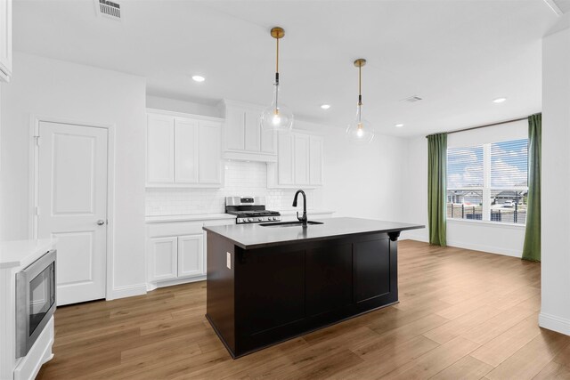 kitchen featuring an island with sink, stainless steel appliances, sink, and white cabinetry