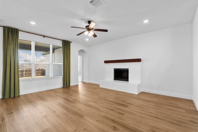 unfurnished living room with a fireplace, light wood-type flooring, and ceiling fan