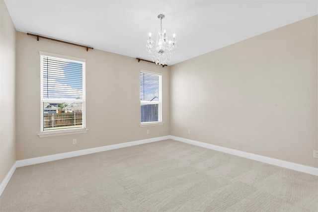 carpeted empty room featuring a chandelier