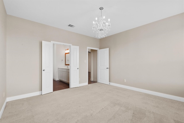 unfurnished bedroom featuring carpet floors, ensuite bath, and a chandelier