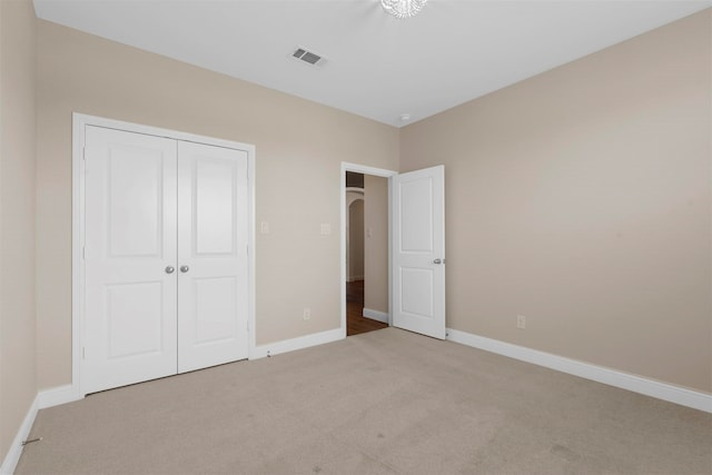 unfurnished bedroom with light carpet and a closet