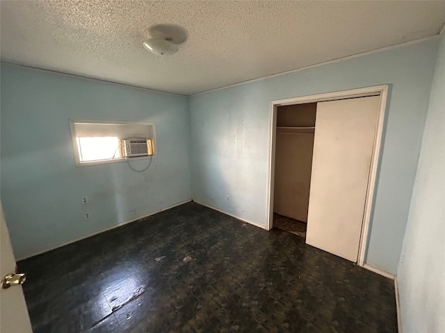 unfurnished bedroom featuring a closet, a wall mounted AC, dark hardwood / wood-style flooring, and a textured ceiling