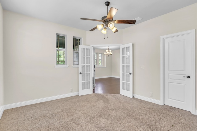 spare room featuring ceiling fan with notable chandelier, french doors, and carpet flooring